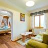 Zimmer im Höchbauernhof, © zVg Gemütliches Zimmer mit Holzmöbeln, grünem Sofa, großem Fenster und einem Himmelbett im Hintergrund.