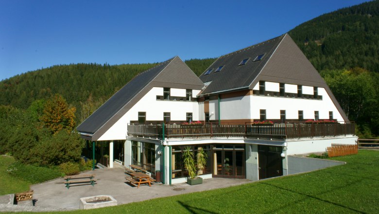 Junges Hotel Annaberg, © zVg Gemeinde Annaberg Ein modernes Gebäude mit spitzem Dach in einer grünen Landschaft.