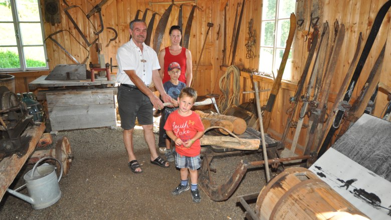 Hausstein Mountain Farm Museum, © zVg Family in a traditional wooden hut with old farming equipment.