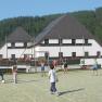 Young Hotel Annaberg, © zVg Gemeinde Annaberg Children play soccer on a sports field in front of a hotel in a wooded area.