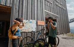 Ein Paar, bestehend aus einem Mann und einer Frau, erkundet die Umgebung am Hennesteck auf rund 1300 Metern Höhe bei den Annaberger Liften am Annaberg mit dem Fahrrad und fährt über alpine Wege durch die Berglandschaft.