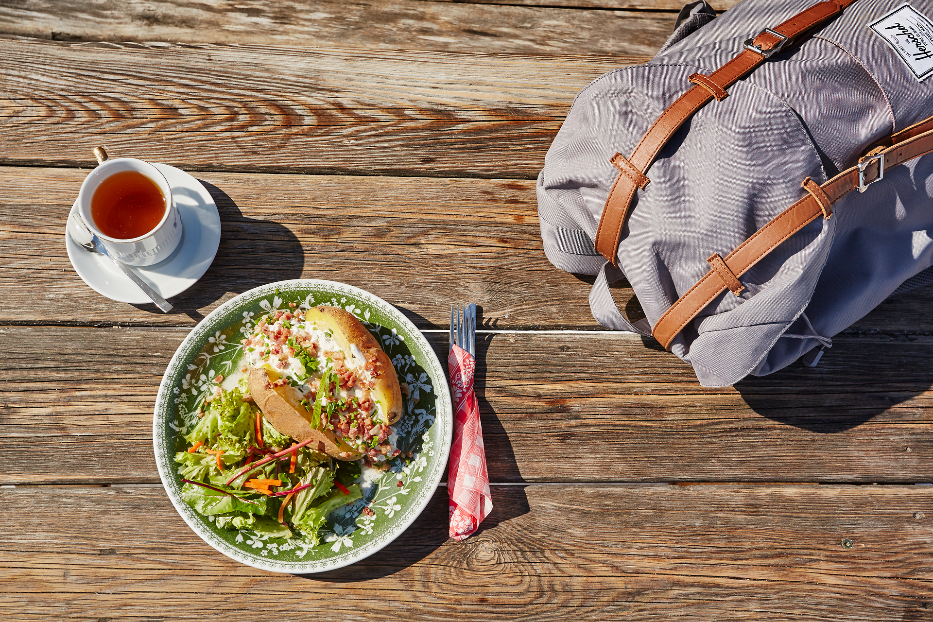 Genießen Sie eine köstliche Mahlzeit inmitten der Natur, während die Sonne sanft über die Berge scheint. Der frisch zubereitete Salat und die herzhaften Speisen laden dazu ein, die Schönheit des Moments zu erleben. Ein perfekter Ort, um sich zu entspannen und die Aussicht zu genießen.