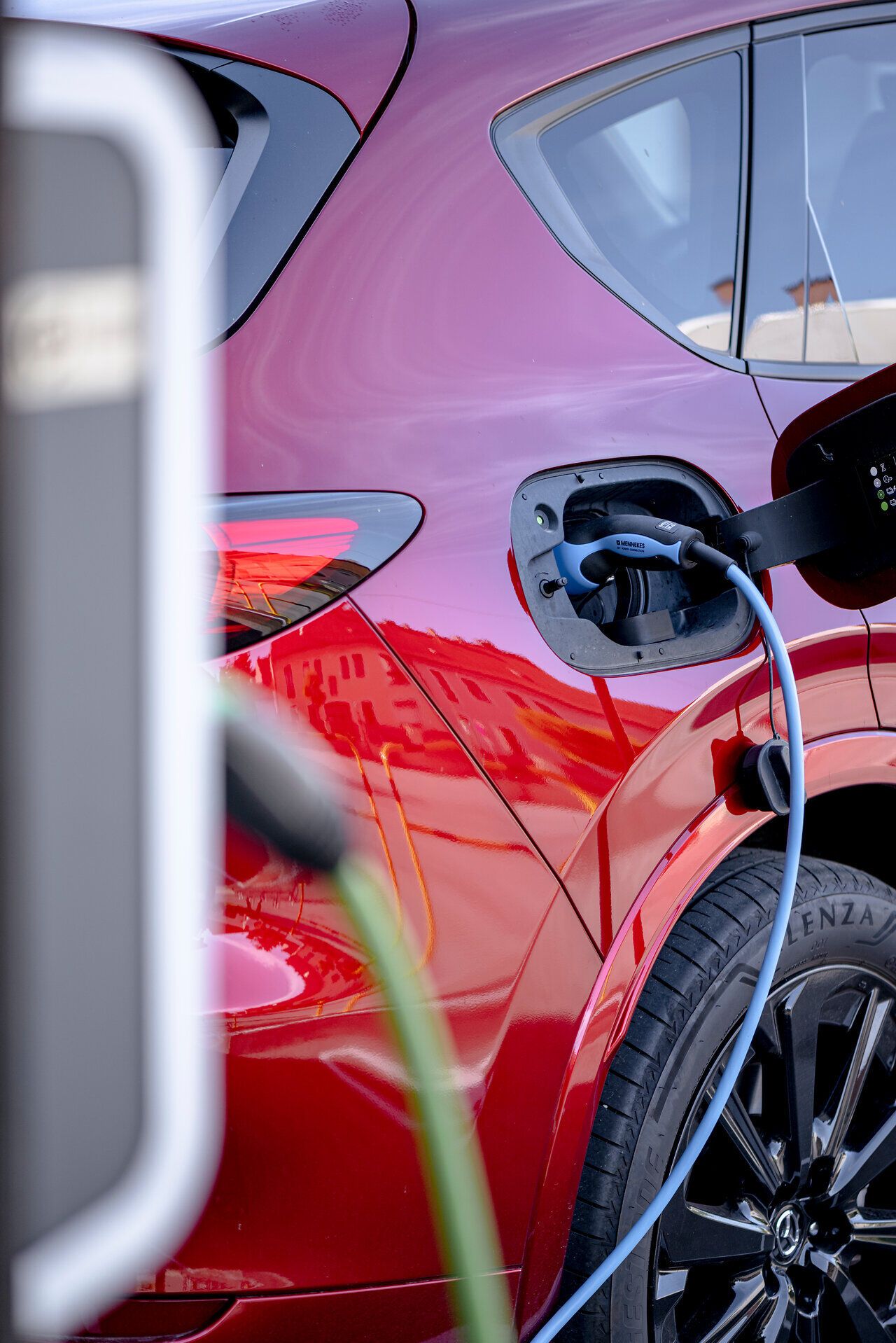 Rotes Auto steckt an einer E-Ladestation. 
