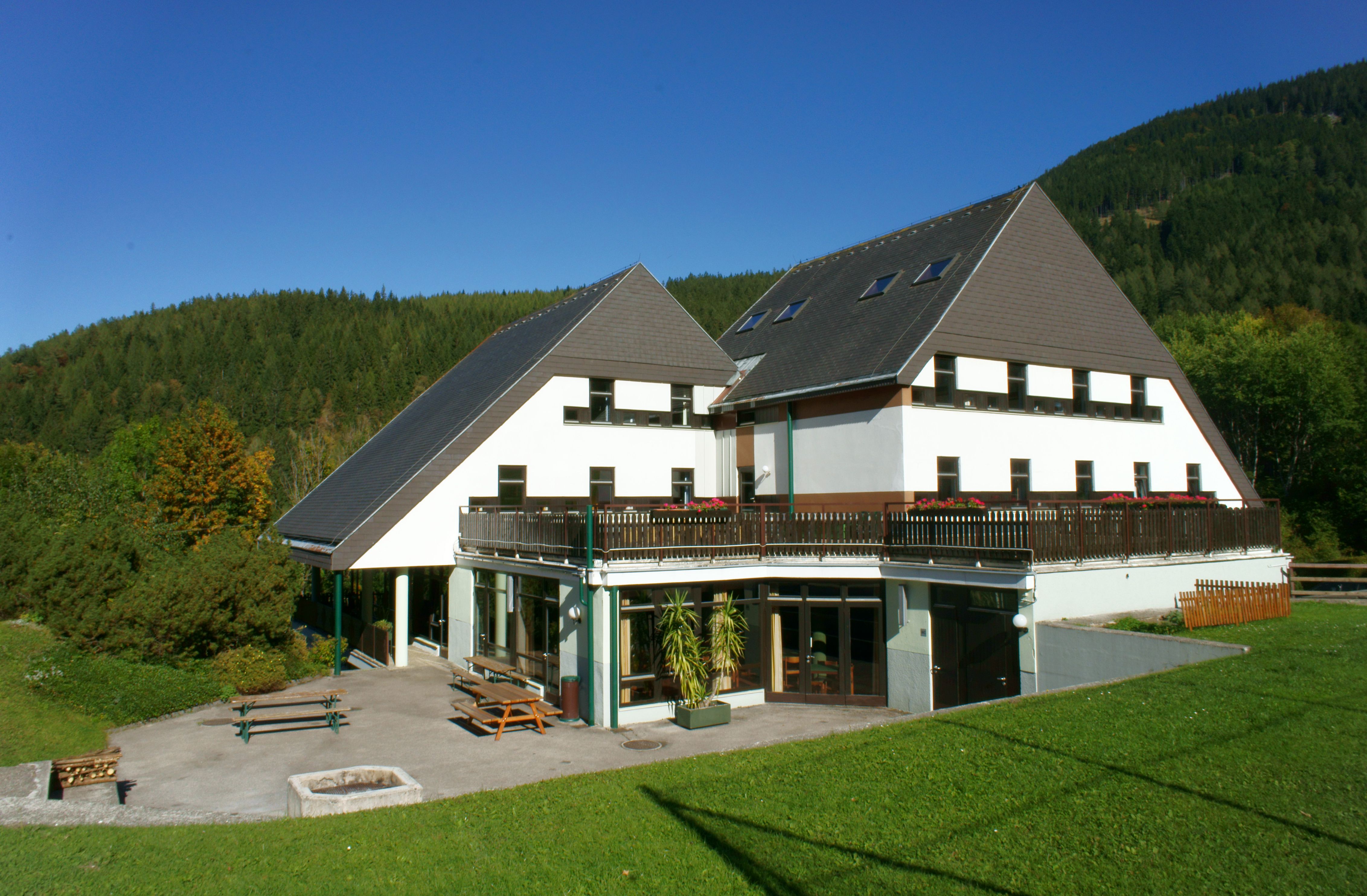 A modern building with a pointed roof in a green landscape.