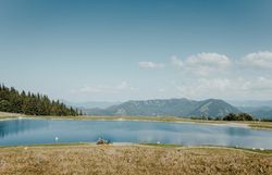 Ein Mann und eine Frau erkunden die Umgebung rund um den Speichersee am Hennesteck am Annaberg mit dem Fahrrad. Sie sind auf den Wegen rund um den See unterwegs und entdecken dabei die alpine Landschaft mit ihren Bergen, Wiesen und Aussichtspunkten.