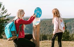 Eine Mutter liest ihrem Kind von einer der vielen spannenden Tafeln vor, welche es bei Nikis Alm-Abenteuer zu finden gibt.