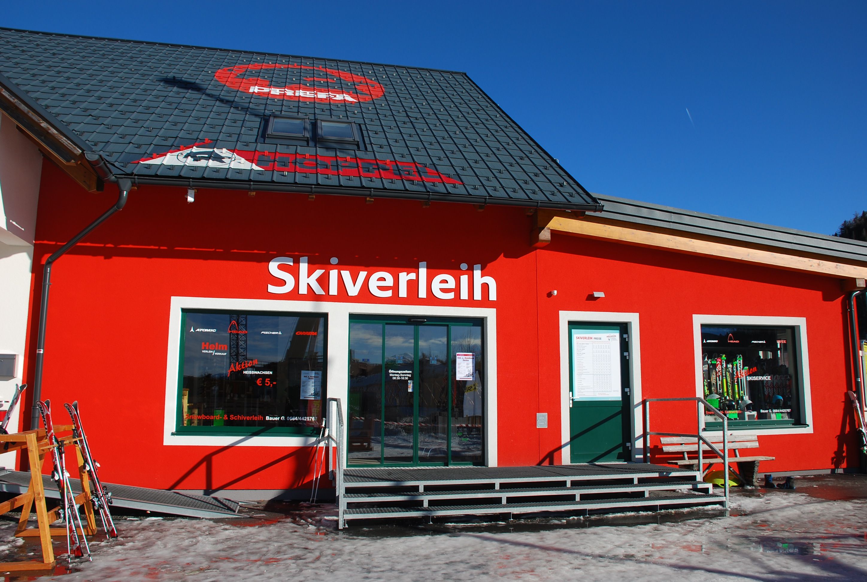 A red building with the words 'ski rental' and ski equipment in the shop window.