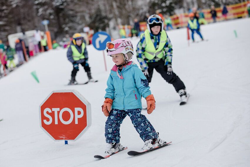 Ein fröhliches Kinderlachen erfüllt die Luft, während die kleinen Skifahrer mit Begeisterung die Pisten hinuntergleiten. Die strahlenden Farben ihrer Kleidung heben sich lebhaft vom glitzernden Schnee ab, und die frische Bergluft sorgt für ein unvergessliches Winterabenteuer.