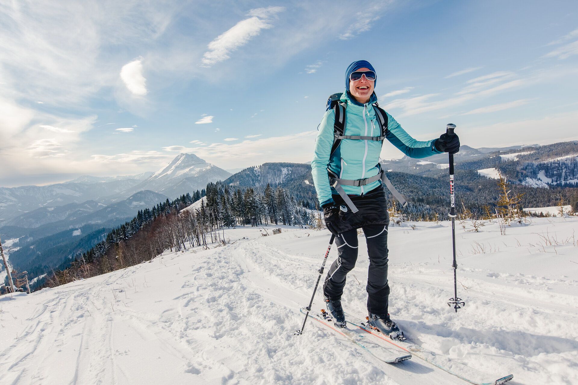 Eine fröhliche Skitouristin genießt die frische Winterluft und die atemberaubende Aussicht auf die schneebedeckten Berge. Umgeben von der unberührten Natur und dem glitzernden Schnee, strahlt sie vor Freude und Abenteuerlust. Der Ötscherblick bietet eine perfekte Kulisse für unvergessliche Erlebnisse in den Alpen.