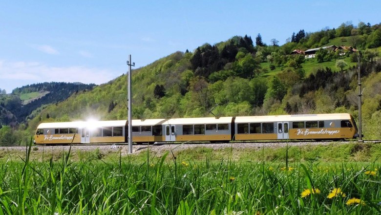 Die Himmelstreppe fährt durch eine grüne, sanft hügelige Landschaft.