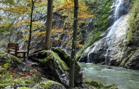Bank am Fluss im Naturpark &Ouml;tscher Torm&auml;uer mit Wasserfall und herbstlichen B&auml;umen.