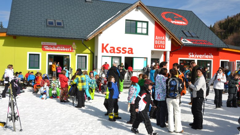 Menschenmenge vor einem Skigebäude mit Kassa, Skiverleih und Teichstüberl.