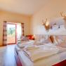 Hotelzimmer mit Doppelbett, Holzmöbeln und Balkon mit Bergblick.