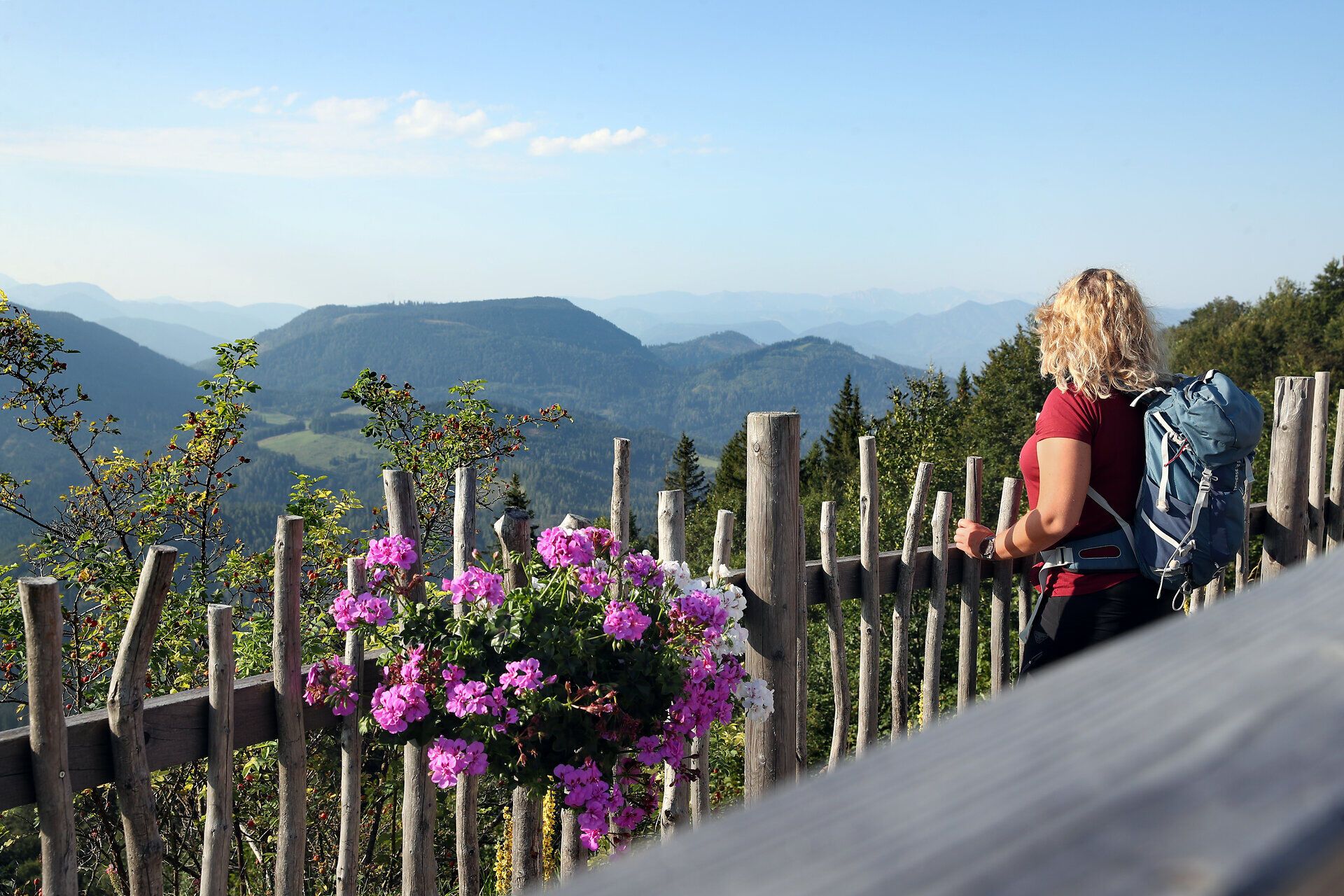 Eine blonde Frau wandert am Annaberg mit Ausblick auf beeindruckende Bergkulissen und die umliegende Landschaft.