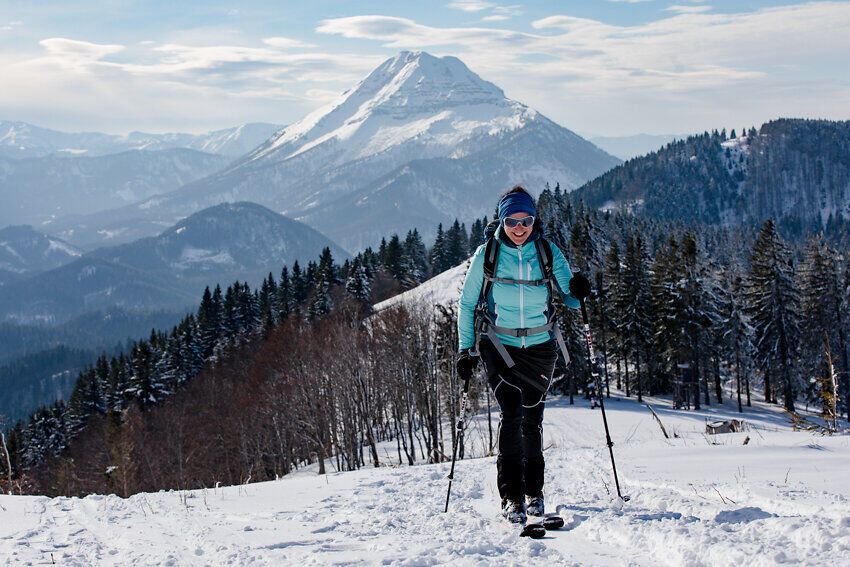 Die glitzernde Schneedecke erstreckt sich über die sanften Hügel, während die strahlende Sonne den Himmel erleuchtet. Ein fröhlicher Wanderer genießt die frische Bergluft und die atemberaubende Aussicht auf die majestätischen Gipfel der Umgebung. Hier in den Mostviertler Bergen wird jeder Schritt zu einem unvergesslichen Erlebnis.
