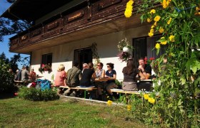 People sit at tables outside a farmhouse.